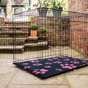 Charcoal Vet Fleece mat with pink paw prints placed inside a metal dog crate outdoors.
