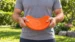 The orange XL DuraToy Flying Disc being bent almost double by hand, showing how far the rubber flexes